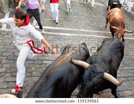 PAMPLONA, SPAIN -JULY 14: Unidentified men run from bulls in street Estafeta during San Fermin festival in Pamplona, Spain on July 14, 2013.