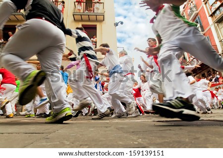 PAMPLONA, SPAIN-JULY 12: People run from bulls on street during San Fermin festival in Pamplona, Spain on July 12, 2013