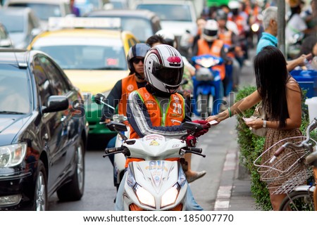 BANGKOK - FEBRUARY 28: A woman pays for the service motorcycle taxi on the street Bangkok Thailand, February 28, 2014. A common way of move the local people in Thailand.