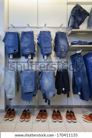 Jeans, trousers and shoes in retail shop interior. Store display with rack, shelf.