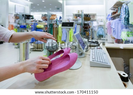 Woman hands holding price scanner. Fashion clothing store. Cashier register,  computer on sales counter in shop. Shoes, pricing, shopping.