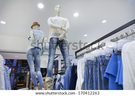 Shop interior with mannequin, dummy.  Row of clothing hanging on rack in retail store.