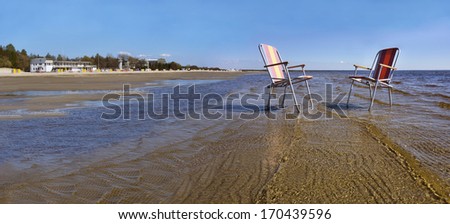 Two beach chairs in water. Outdoor furniture on a beach in Estonia. Baltic Sea.