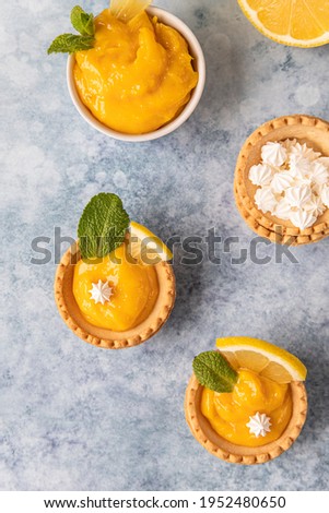 Mini tarts with lemon curd, mini meringue, lemon slices and mint on blue concrete background. Top view. Selective focus. Stok fotoğraf © 