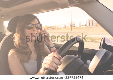 Young woman driving at sunset whit a mobile phone. Filtered picture with vintage effects.