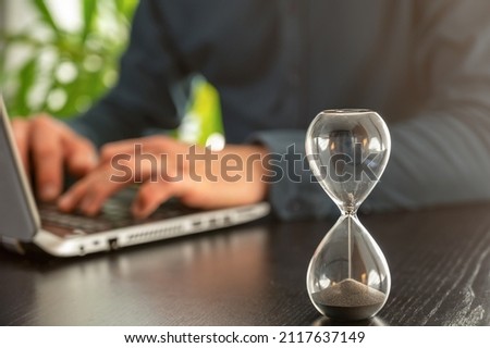 Hourglass with time running out in an office as a symbol of time pressure at work Foto d'archivio © 