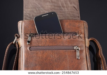 Mobile phone in the pocket of leather messenger bag
