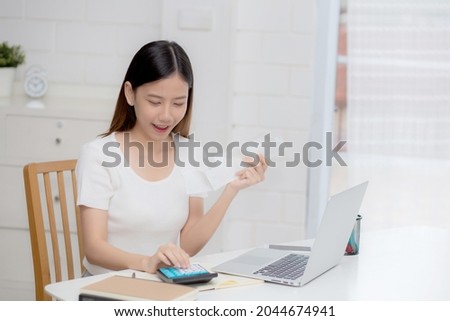 Young asian woman calculating finance household with calculator on desk at home, girl checking bill and success for saving expenses household, debt closure, tax and accounting, business concept.