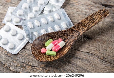 pills in a wooden spool and various pills pile of medicine on a table