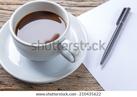 Cup of coffee, pen and paper on wooden table