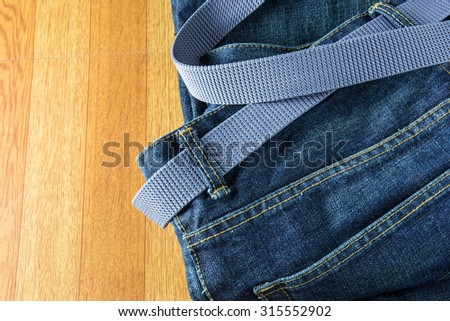Blue jeans with belt on wooden background