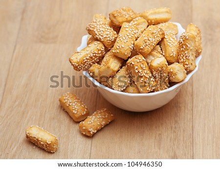Bread sticks sprinkled with sesame seeds on wooden table.
