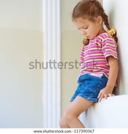 Beautiful Little Girl In Shorts Sitting On Stone Ledge, And Sad. Stock ...