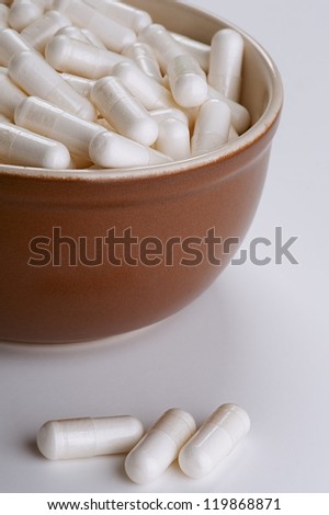 Many medicinal pills on brown plate.