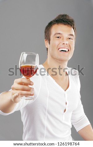 Young handsome man lifts toast about wine glass, on gray background.
