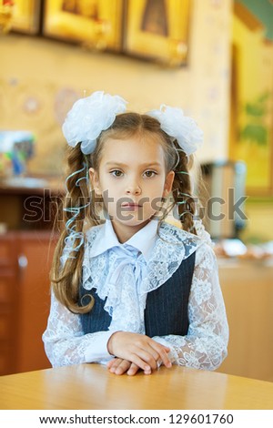 Beautiful little girl with big white bows around table.
