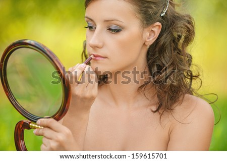 portrait pretty young woman bare lipstick contour pencil looks mirror, background summer nature