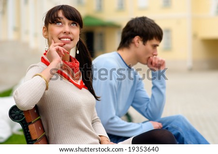 Young man and woman sit on city bench and think.