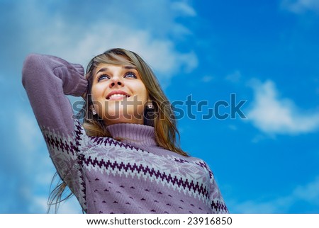 Young beautiful woman has rest, having combined hands behind head, and smiles, against dark blue sky.