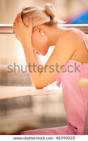 Beautiful young woman has clasped hands head and has leant the elbows on table.