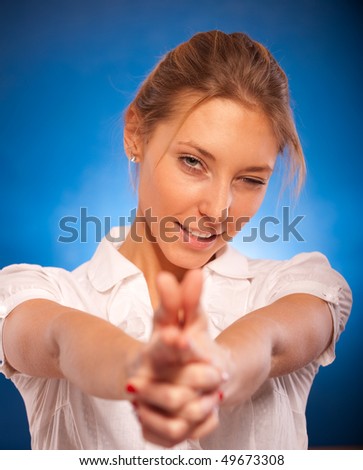 Young beautiful woman shoots, having connected fingers, on dark blue background.