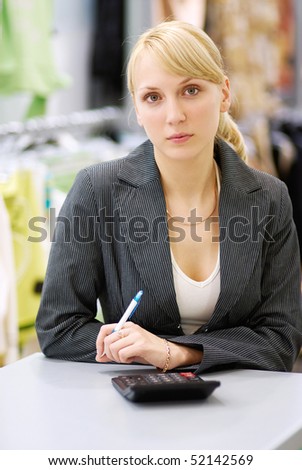 Young beautiful woman behind a table with  calculator and  pen in hands