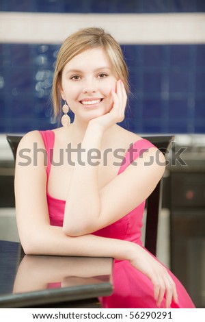 Smiling girl in red dress sits at table