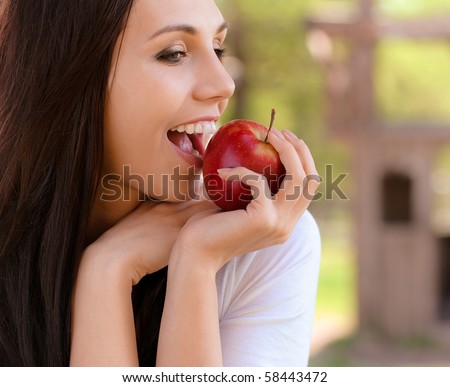 Smiling young woman bites red apple