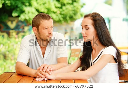 Young couple sit at little table in summer cafe.