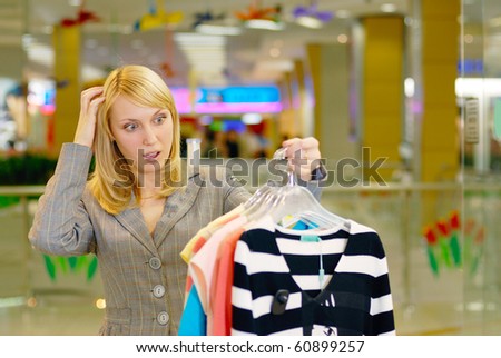 The young beautiful woman has difficulty in a question of acquisition of clothes