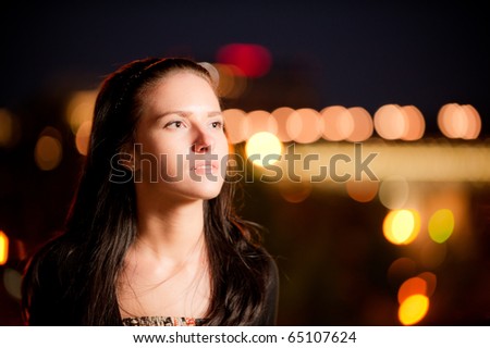 Portrait of charming dark-haired girl against night city.