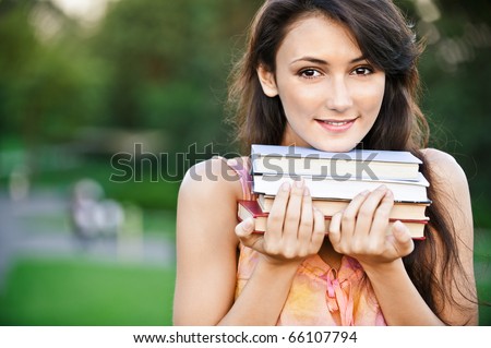 Girl-student holds textbooks, against summer garden.