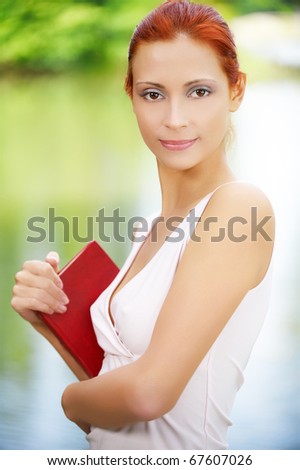 portrait of beautiful red-haired student with book outdoors