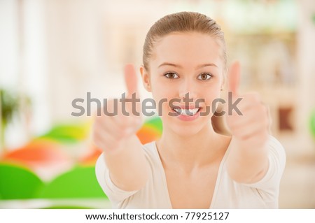 Beautiful young woman lifts thumbs meaning that all perfectly.
