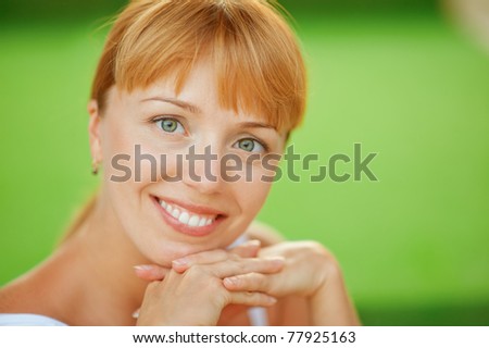 Young beautiful woman close up smiles, on green background.