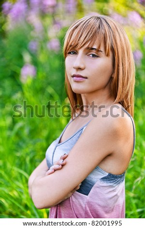 Portrait of young beautiful content blond woman at summer green park.
