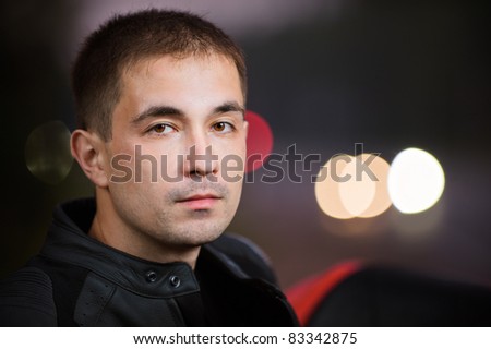 Portrait of handsome dark-haired young man against traffic lights.