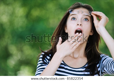cute young woman looking up surprised raised glasses covers mouth his hand