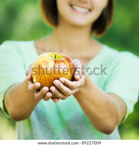young beautiful woman long hair park offering yellow apple