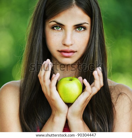 portrait pretty serious long-haired woman hands yellow apple background summer park