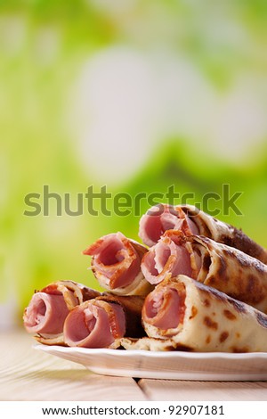 on green background, meat rolls (bacon, ham) in the pancakes