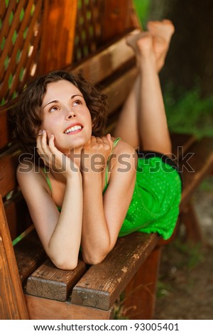 outside portrait of young beautiful happy woman laying on bench in park