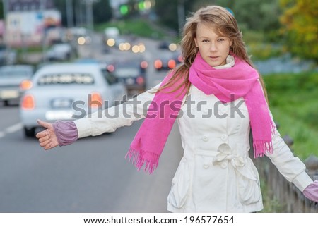Beautiful young woman with pink scarf vote on city road.