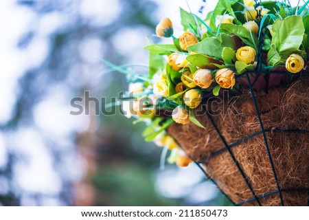 Artificial flowers in decorative basket in garden of summer.