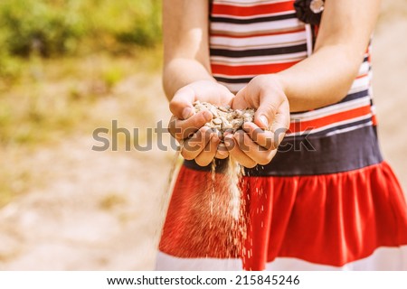 Little girl throws sand from palms.