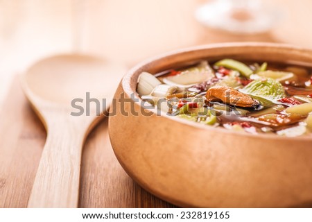 Thai Tom Yam soup with seafood in plate on wooden table.