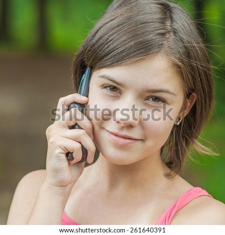 Young charming girl talks by mobile phone and laughs.