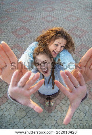 Two beautiful young women on background of paving slabs.