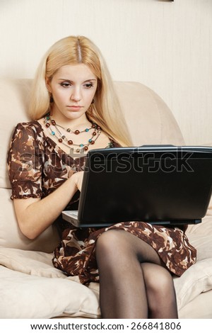 Young charming fair-haired woman works on portable computer.