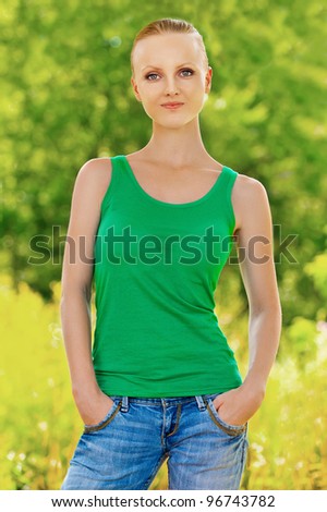 Portrait of pretty young fair-haired woman wearing t-shirt at summer green park
